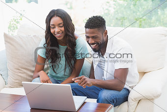 Happy couple on the couch using laptop
