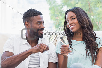 Happy couple on the couch having champagne