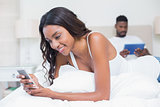 Relaxed couple using technology on bed