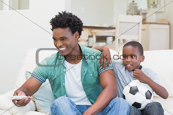 Father and son watching tv together on the couch