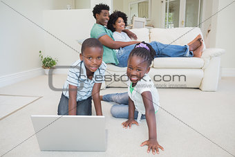 Happy siblings sitting on the floor using laptop