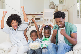 Happy family watching television eating popcorn