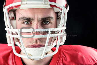Portrait of a serious american football player taking his helmet looking at camera