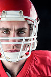 Portrait of a serious american football player taking his helmet looking at camera