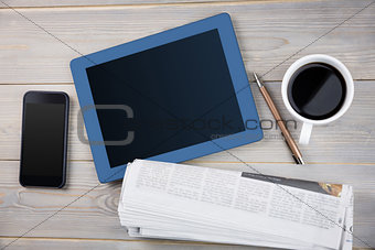Tablet next the cup of coffee smartphone and newspaper