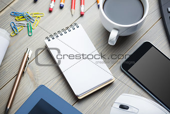Notepad next to the cup of coffee smartphone mouse and tablet