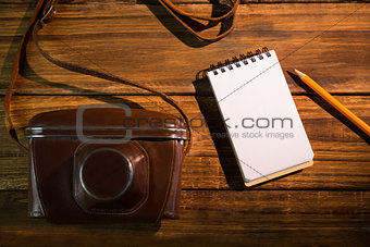 Notepad next to camera and pen