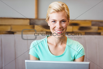 Happy pretty blonde using computer and looking at camera