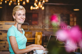 Pretty blonde looking at camera and using laptop computer
