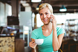 Pretty blonde woman using her smartphone with a cup of coffee
