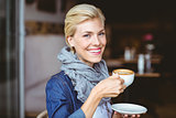 Smiling blonde enjoying a cup of cappuccino