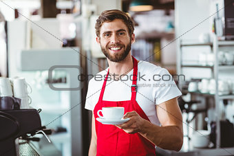 Handsome barista holding a cup of coffee
