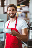 Handsome barista holding a cup of coffee