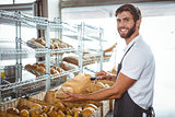 Cheerful worker standing and presenting a bread
