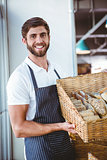 Portrait of happy worker holding basket of bread