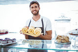 Smiling worker holding pastry behind the counter