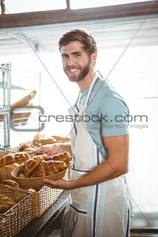 happy worker holding a basket of croissant