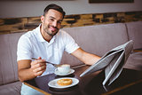 Young man having cup of coffee and eating pastry