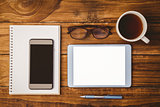 Smartphone on notepad next to tablet and glasses and cup of coffee