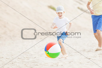 family playing with ball at the beach