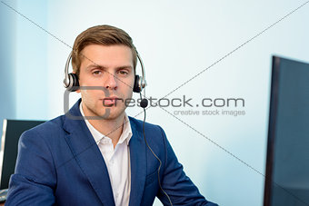 Young Customer Support Phone Operator with Headset at his Working Place in Office.