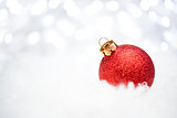 Christmas Decoration with Red Ball in the Snow on the Blurred Background with Holiday Lights. Greeting Card
