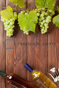 Bunch of grapes, white wine bottles and corkscrew