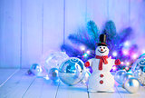 Christmas snowman with balls and garland on wooden board