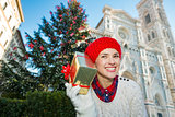 Happy woman holding gift box near christmas tree in Florence