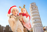 Mother in Christmas hat and daughter giving air kiss in Pisa