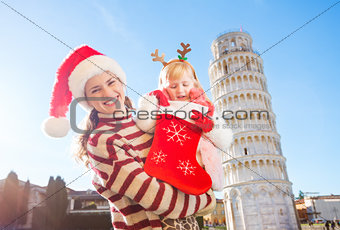 Mother with daughter looking into Christmas sock for gift, Pisa