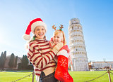 Mother with daughter pulling out gift from Christmas sock, Pisa