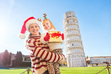 Mother in Christmas hat and daughter holding gift box. Pisa