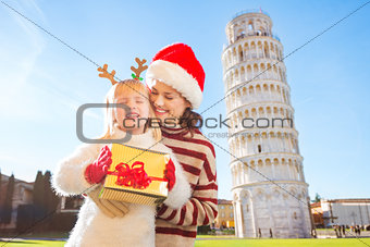 Woman in Christmas hat and baby girl holding gift box. Pisa