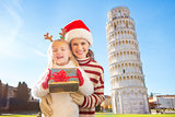 Woman and baby girl with gift box spending Christmas in Pisa