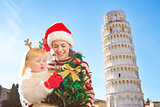 Happy mother and daughter holding Christmas tree. Pisa, Italy