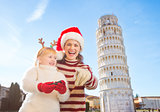 Girl with mother in Christmas hat pointing in camera. Pisa