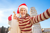 Mother in Christmas hat taking selfie with daughter in Pisa