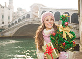 Smiling woman with Christmas tree and gift box in Venice, Italy