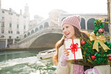 Happy woman with Christmas tree and gift box in Venice, Italy