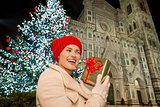 Young woman with gift box near Christmas tree in Florence, Italy
