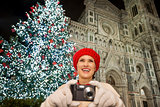 Young woman taking photos near Christmas tree in Florence, Italy