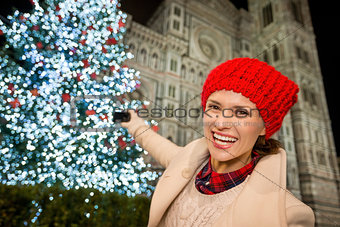 Happy woman taking photos of Christmas tree in Florence, Italy