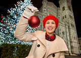 Happy woman showing Christmas ball near Duomo in Florence, Italy