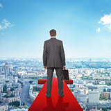 Businessman on red arrow above city