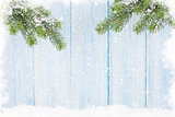 Christmas fir tree in snow in front of wooden wall