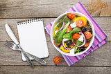 Fresh healthy salad and notepad for copy space