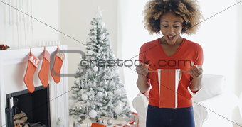 Happy young woman opening Christmas gifts