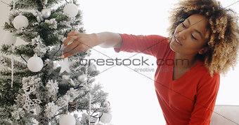 Pretty young African woman decorating an Xmas tree