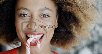 Fun young woman biting Christmas candy cane